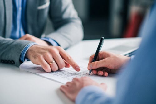 Person points to document to sign - avoid real estate scams